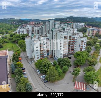 Luftaufnahme eines Wohngebiets mit großen Wohnhäusern, umgeben von Bäumen und Grünflächen, mit den Hügeln von Tuzla im Hintergrund Stockfoto