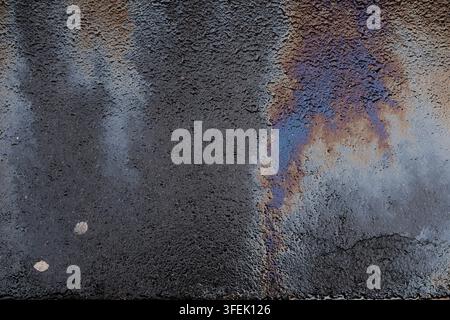 Ein farbenfroher, schimmernder Ölfilm auf dem Asphalt; es hatte früher geregnet, und der Boden ist nass Stockfoto
