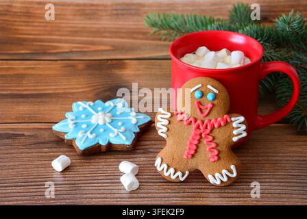 Lebkuchenmann und Schneeflockenkuchen mit heißer Schokolade auf Holztablett dekoriert mit Kiefernzweig Stockfoto