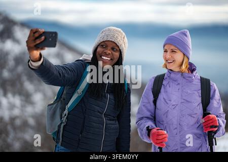Verschiedene Frauenfreundinnen nehmen ein Selfie während einer Winterbergwanderung Stockfoto