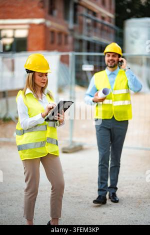 Weibliche und männliche Ingenieure besprechen Pläne und kommunizieren auf einer Baustelle Stockfoto
