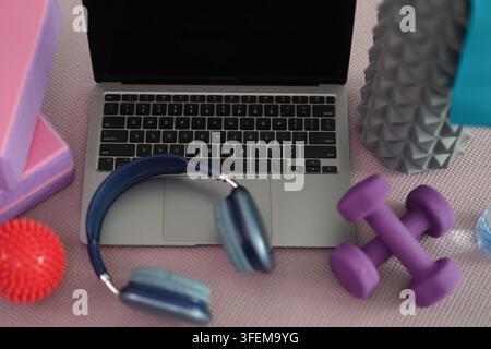 Laptop und Trainingsgeräte auf Yogamatte zu Hause angeordnet Stockfoto