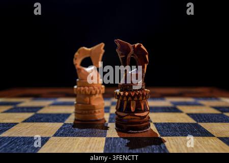 Zwei hölzerne Schachspringer, die sich auf einem Schachbrett gegenüberstehen Stockfoto
