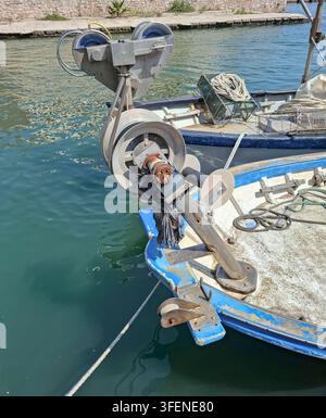 Eine mechanische hydraulische Netzschlepperwinde ist am Bug eines kleinen Fischerboots montiert, das in einer Marina vertäut ist. Die Winde ist für Fischereieinsätze ausgelegt Stockfoto