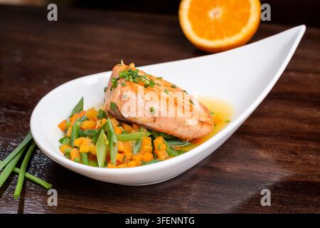 Gegrilltes Lachsfilet mit frischem Gemüse und Zitrus-Sauce in Gourmet-Präsentation Stockfoto