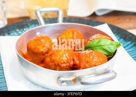 Traditionelle Fleischbällchen serviert mit Basilikumblatt und Tomatensauce. Italienisches Restaurant Osteria in Turin, Norditalien. Stockfoto