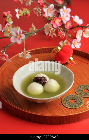 Grüner Tee Big Tangyuan und Matcha-Suppe auf Holztablett über rotem Tisch. Stockfoto