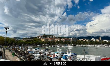 Fischerboote und kleine Schiffe, die im Yachthafen von La Spezia, Italien, entlang der ligurischen Küste vertäut sind. Dramatische Wolken füllen den Himmel über dem Ufer Stockfoto