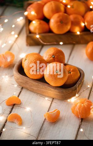 Tangerinen in einer Holzschale mit Lichterketten Stockfoto