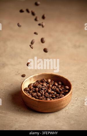 Fallende geröstete Kaffeebohnen in einer Holzschale Stockfoto