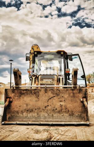 Komatsu-Baggerlader mit einem schmutzigen Vorderbaggerschaufel, geparkt auf einer Baustelle unter einem bewölkten Himmel in der Festung der Stadt Oradea Stockfoto