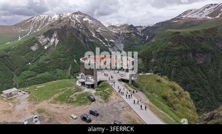 Luftaufnahme des Georgia-Russland-Freundschaftsdenkmals, einer kreisförmigen Struktur mit Wandgemälden, auf einem Bergrücken mit Touristen, die auf dem Weg in Gani gehen Stockfoto