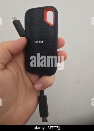 Nahaufnahme eines robusten tragbaren SSD-Speichergeräts, das für die digitale Datensicherung und Dateiübertragung verwendet wird, im Innenraum in der Hand gehalten. Stockfoto