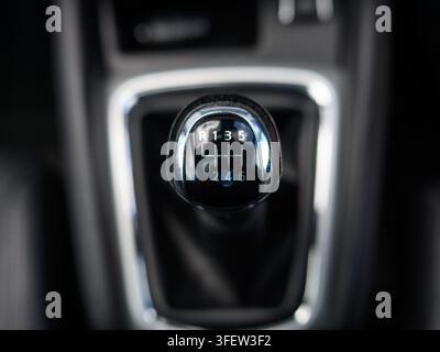 Nahaufnahme eines Auto-Schaltknaufs. Die Zahlen 1 bis 6 und R sind beschriftet. Moderner Fahrzeuginnenraum als Hintergrund. Zeigt Details des Schaltgetriebes. Ideal Stockfoto