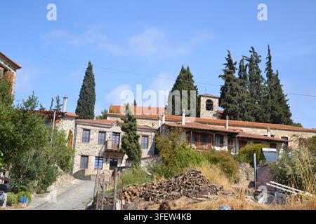 Traditionelles griechisches Dorf mit Steinhäusern, Terracotta-Dächern und Zypressen unter einem blauen Himmel, Griechenland, Europa. Stockfoto