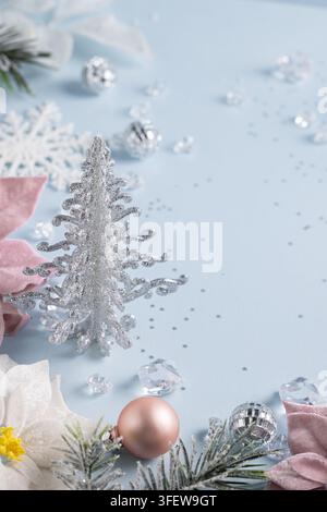 Silberner Weihnachtsbaum neben pinker Weihnachtsstern auf blauem Hintergrund mit breitem Kopierraum für Neujahrsbanner oder festliches Produktdesign Stockfoto