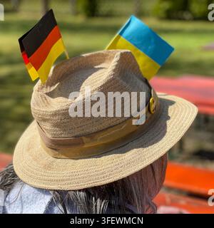 Ein Mann, der einen Strohhut mit den deutschen und ukrainischen Flaggen darauf trägt Stockfoto