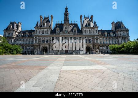 Breite Ansicht der historischen neorenaissance Fassade des Hôtel de Ville und des großen offenen Platzes unter einem blauen Himmel in Paris, Frankreich. Stockfoto