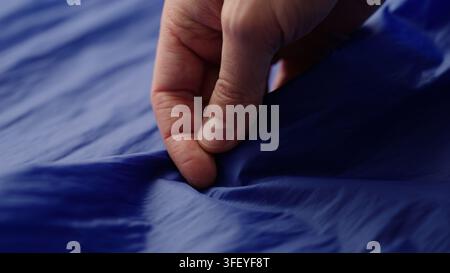 Männerhand prüft blauen Kunststofftaschenstoff Stockfoto