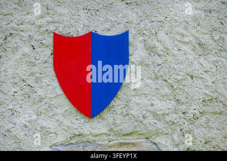 Nahaufnahme des lebendigen roten und blauen Schildes, der das offizielle Wappen des Kantons Tessin auf einer strukturierten Steinmauer in Lugano darstellt Stockfoto