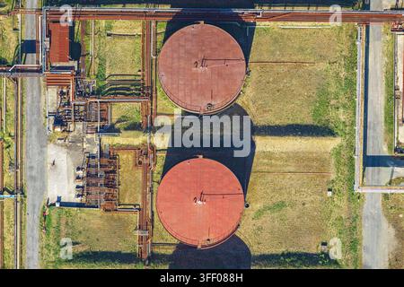Luftaufnahme von zwei großen runden Industrie-Speichertanks, umgeben von einem komplexen Netz aus Rohren und Infrastruktur in La Spezia, Ligurien, Italien. Stockfoto