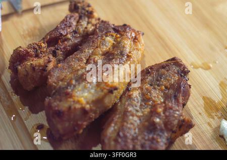 Knusprige Schweinebauch-Häppchen: Nahaufnahme von herzhaften, knusprigen Schweinebauchstücken, die vor Saft glänzen und bereit sind, genossen zu werden, mit einer Gabel und einem Messer bereitgehalten Stockfoto
