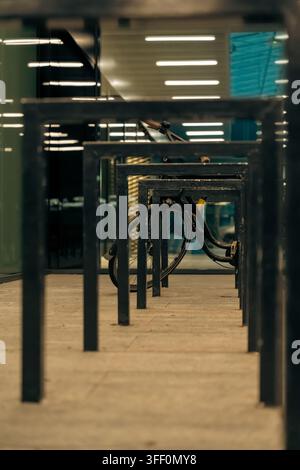Ein schwarzes Fahrrad mit braunen Lederlenkergriffen ist in einer Reihe dunkler Metallparkrahmen eingeschlossen, die sich in der Ferne verlieren auf einem hellen Dach Stockfoto