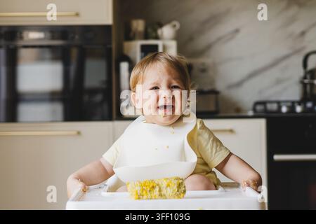 Unzufriedenes Baby weigert Nahrung, während es zu Hause in einem Hochstuhl sitzt Stockfoto