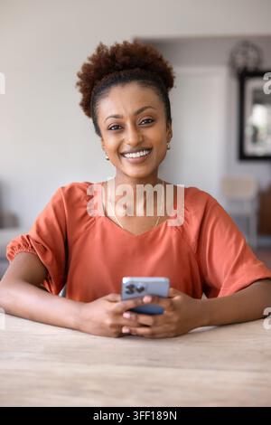 Porträt einer lächelnden afrikanischen Frau, die ein Smartphone hält Stockfoto