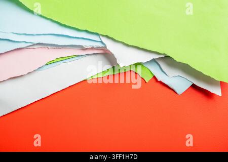 Lebendige abstrakte Komposition aus geschichteten, zerrissenen farbigen Papierblättern in Rot, Grün, Blau, Rosa und Weiß mit grob gerissenen Kanten Stockfoto