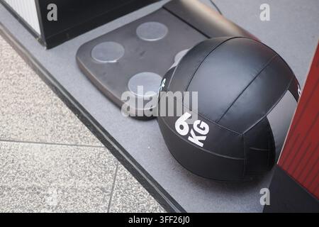Schwarzer 6kg-Medizynbalsam auf Fitnessstudio-Boden neben Balance-Plate für funktionelles Fitnesstraining Stockfoto
