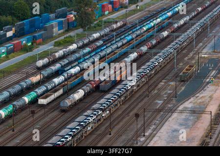 Polen – 27. August 2026: Luftaufnahme eines geschäftigen Containerterminals und eines Bahnhofsgeländes mit mehreren Güterzügen, Tankwagen und einem Autotransporter Stockfoto