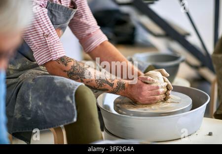 Nahaufnahme auf die Hand eines Mannes, der einen nassen Tontopf auf der Töpferscheibe formt. Kreatives Hobby, Aktivitätenkonzept Stockfoto