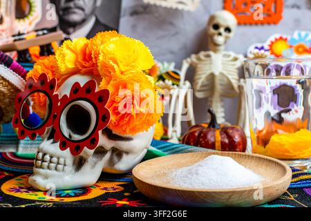 Dia de Muertos-Altar mit einem verzierten Schädel, Ringelblumen und traditionellen Opfergaben Stockfoto