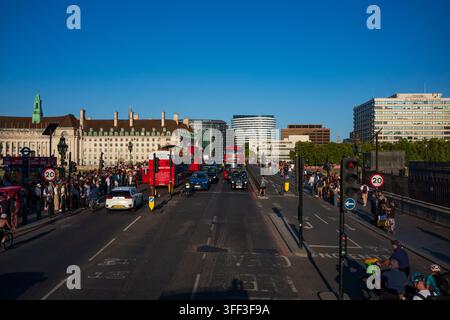 London, England, UK, 11. Aug. 2026: Eine belebte Westminster Bridge, gesäumt von Autos, Bussen, Radfahrern und Fußgängern, an einem späten Nachmittag ohne Wolken Stockfoto