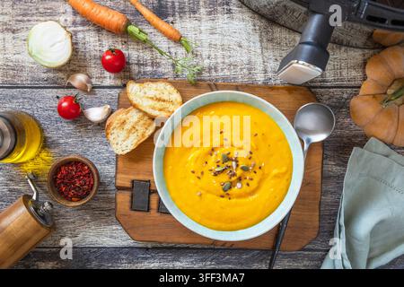 Schüssel mit vegetarischer Kürbissuppe und Toasts auf Holzunterlage. Gesundes Essen, Essen. Lifestyle-Trends des neuen Kochens. Top-Down-Flächenlayout-Hintergrund. Stockfoto