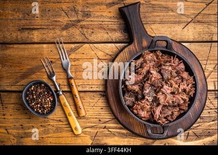 Barbecue-Wagyu-Fleisch in Stücken, gezogenes Rindfleisch in einer Pfanne. Holz-Hintergrund. Oberansicht Stockfoto
