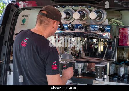 Barista bedient eine große Kaffeemaschine von der Rückseite eines mobilen Kaffeewagens oder Fahrzeugs. Stockfoto