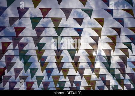 Bunte dreieckige Wimpel flags hängen vor dem Himmel als festliche Straßendekoration im Freien. Stockfoto
