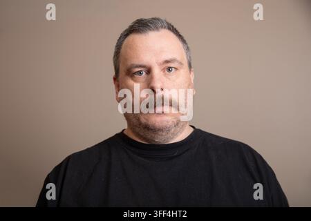 Mann mit graumeliertem Haar und Schnurrbart schaut direkt in die Kamera Stockfoto
