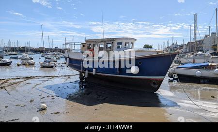 St Aubin, Jersey, Kanalinseln – 31. August 2026: Ein verwittertes Boot ruht auf dem freiliegenden Hafenbett bei Ebbe in St Aubin’s Hafen. Stockfoto
