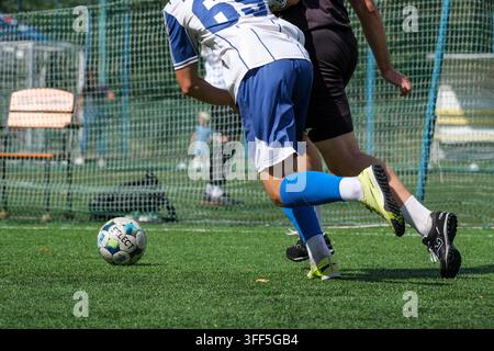 Kiew, Ukraine – 05. September 2026: Futsal-Spieler in blauer und weißer Uniform beschützt den Ball vor einem Verteidiger während eines Outdoor-Mini-Football-Turniers Stockfoto