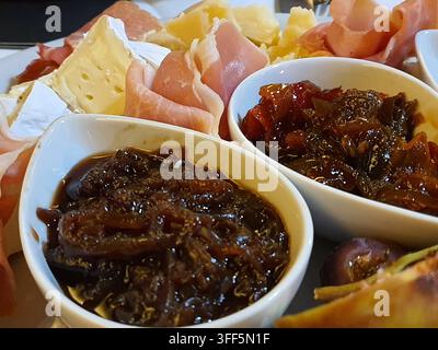 Nahaufnahme eines Gourmet-Vorspeisentellers mit einer Auswahl an gepökelten Fleischsorten, darunter dünn geschnittener Prosciutto und Schinken, gepaart mit verschiedenen Stockfoto