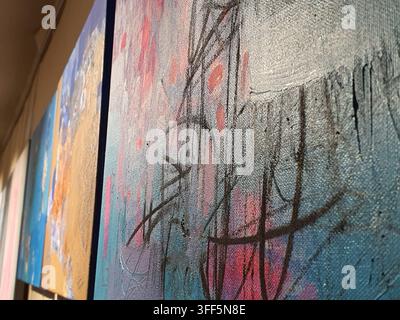 Nahaufnahme einer schrägen Ansicht von abstrakten expressionistischen Gemälden auf Leinwand, die in einer Galerieausstellung gezeigt werden. Das Bild im Vordergrund zeigt texturierte Schichten von Stockfoto