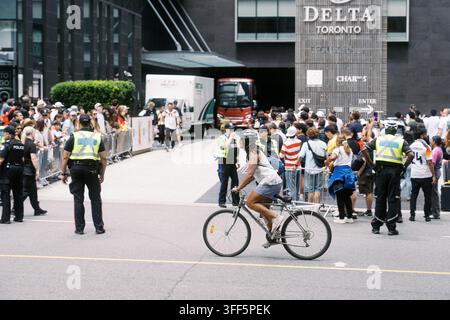 Toronto, Kanada - 20. Juni 2026: Radfahrer fährt an einer Menschenmenge und der Polizei vor dem Delta Toronto Hotel vorbei Stockfoto