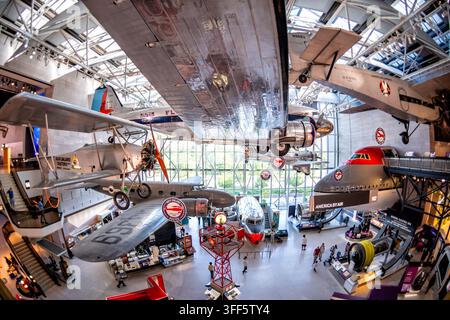 Vintage-Flugzeuge in Amerika in der America by Air-Galerie in Washington DC | WASHINGTON D.C., Vereinigte Staaten — Vintage-Flugzeuge hängen Flügelspitze an Flügelspitze über der America by Air-Galerie des National Air and Space Museum. Die polierte DC-3 und Ford Trimotor spüren den kommerziellen Flug von umgebauten Postflugzeugen zu den druckdichten Jets nach, die den Massenflugverkehr zur Routine machten, Teil des renovierten Mall-Gebäudes des Museums, das anlässlich seines 50. Jahrestages im Jahr 2026 wiedereröffnet wurde. Stockfoto