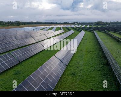 Drohnen-Luftaufnahme einer Photovoltaikanlage mit Reihen von Panelen und grüner Landschaft Stockfoto