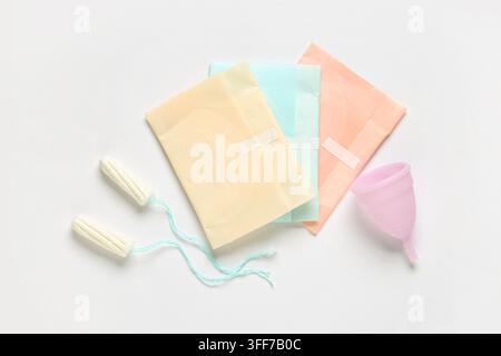Menstruationspads mit Tasse und Tampons auf weißem Hintergrund Stockfoto