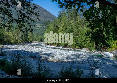 Friedlicher Bergfluss, der durch einen üppigen Wald mit felsigen Ufern fließt, Kettle Valley Trail, BC Kanada Stockfoto