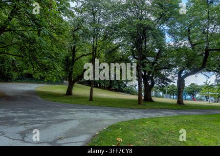 Kurvenreicher Parkweg windet sich durch üppige grüne Bäume und grasbewachsene Hänge, Centennial Way, Burnaby, BC, Kanada Stockfoto